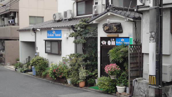 a small house with plants out front and signs for Ryokan Sansui